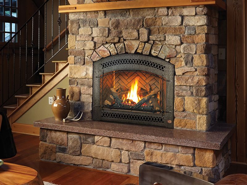 A gas fireplace set into a stone surround beside a staircase