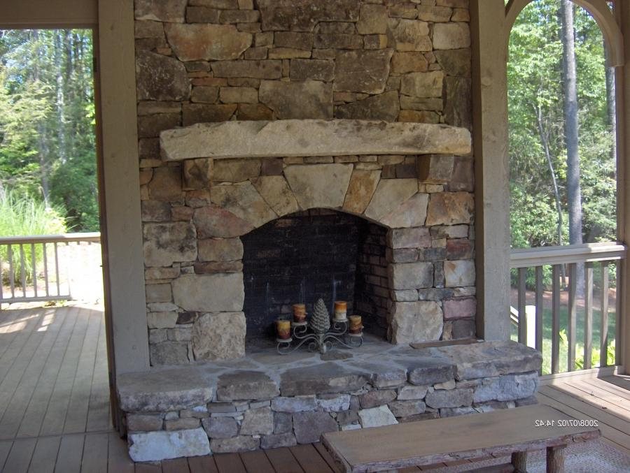 A stone fireplace built into a covered outdoor room