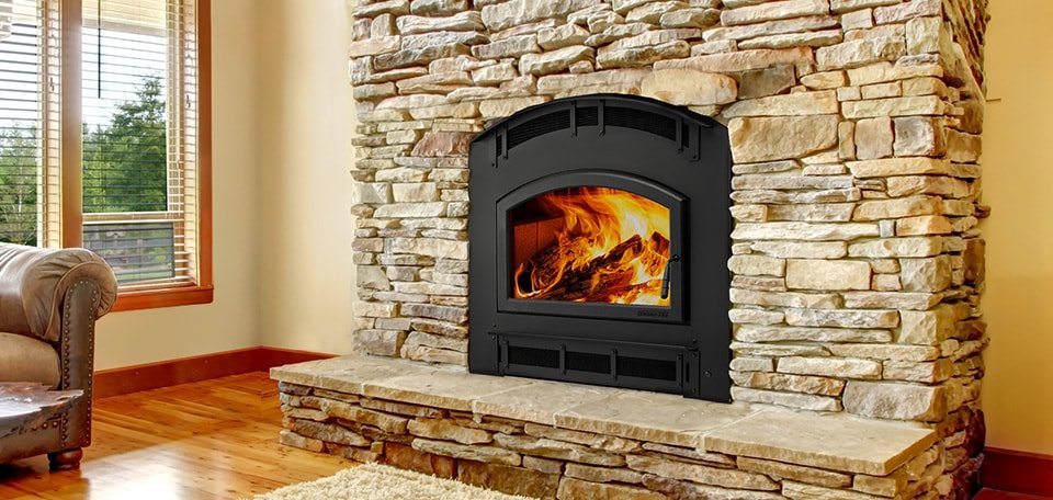 A fireplace built into a stone wall with a window alongside it